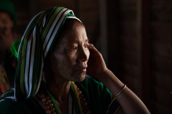 Burma/Myanmar: A Chin woman of an animist village in a remote spot in the vicinity of Mindat. The photo was taken during a special ceremony, in which nine oxen were sacrificed, and their heads hung on poles.