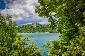 Durch das Blätterdach von Kastanien und Linden schimmert der türkisfarbene Bleder See - darüber thront die mittelalterliche Burg auf ihrem 139 Meter hohen Felsen wie ein Märchenschloss aus längst vergangenen Zeiten.