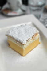 Die legendäre Bleder Cremeschnitte (kremšnita) - seit 1953 gebacken, vereint sie hauchdünnen Blätterteig mit samtiger Vanillecreme und wurde zum süßen Wahrzeichen des Kurorts Bled.