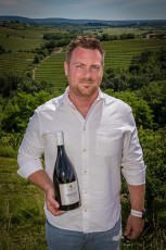 Winzer Patrick Simčič präsentiert stolz seinen 'Moja' vor den terrassierten Weinbergen seines Familienguts - der charismatische Önologe gilt als einer der innovativsten Weinmacher Sloweniens und kultiviert auf 35 Hektar internationale und einheimische Rebsorten.