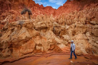 Our guide Christian walks along a stream bed of Tsingy Rouge. These bizarre rock formations of red laterite were created by erosion.
