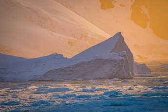 The setting sun behind the Lemaire Channel bathes everything in magical shades of orange and blue.