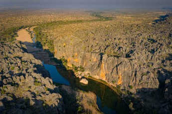 Durch die Jahrmillionen alte Windjana-Schlucht in der Kimberley-Region schlängelt sich der Lennard River wie ein türkisgrünes Band zwischen den bis zu 100 Meter hohen Kalksteinwänden hindurch, die einst ein urzeitliches Barriereriff bildeten und heute Heimat für Süßwasserkrokodile und seltene Gesteinsformationen sind.