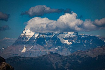 Clouds gather at the summit of Mount Robson, beneath which lie layers of limestone, compressed into horizontal bands over millions of years.