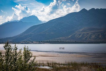 A moment of silence and contemplation amid the sublime nature of the Canadian Rockies: four visitors wade through the mirror-like waters of Lake Jasper.