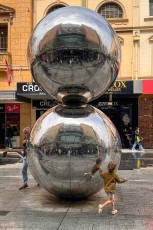 Ein Kind rennt um „Mall's Balls" zu – Adelaides meistfotografierte Skulptur in der Rundle Mall. Die verspiegelten Kugeln sind seit 1977 Treffpunkt, Wahrzeichen und Spielplatz zugleich.