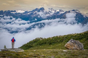 I stay on bare rock, facing a sea of cloud from which the snow-dusted peaks of the Cariboo Mountains emerge (Photo by Jonathan Sprigler)