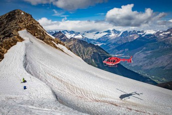 A helicopter hovers over the white, powdery slopes of the Cariboo Mountains and prepares to land – not far from guide Fridjon, who can be made out as a figure in yellow-green, complete with a blue rucksack.