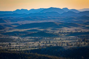Schichtkuchen aus Sandstein und Zeit – Die Sonne taucht die Flinders Ranges in ockergelbe und sienabraune Streifen - gesprenkelt mit dunklen Tupfern vereinzelter Eukalypten.