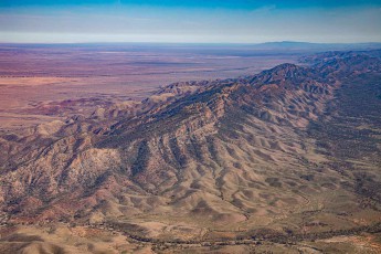 Wind und Wasser haben über Jahrmillionen Rippen ins Gestein der Flinders Ranges gezeichnet, die nun wie versteinerte Wellen gen Horizont laufen. Täler sammeln sich Mulga-Akazien auf ausgedörrtem Boden.