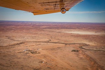 Unter dem Tragflügel der Cessna schichtet sich das Outback in Ocker und Staub bis an den violetten Horizont. Im Vordergrund liegt William Creek, kaum mehr als zwei Handvoll Gebäude – und mit nur etwa 10 Einwohnern wohl die kleinste Stadt Südaustraliens.