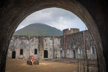 Durch das dunkle Gewölbe öffnet sich der Innenhof, dahinter steht wolkenverhangen der Gunung Api – Fort Belgica entstand ab 1611 auf dem Hügel über der Stadt, um die Muskatnuss zu sichern und die Bandanesen einzuschüchtern.