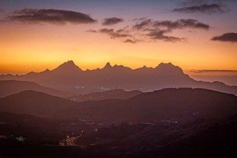 Die letzten Farben des Tages über den Bergen am Horizont, darunter die Lichter einer Siedlung auf São Vicente.