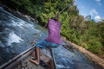 Ein WWF-Boot bringt zwei Lehrerinnen und mich zum letzten Dorf vor der Quelle des Flusses. Das Boot setzt ständig auf und dieser Mann hievt uns immer wieder über die flachen Stellen. Ein Knochenjob.