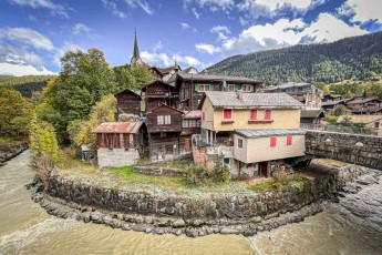 Traditional wooden houses with partly weathered facades along the river Fieschera in Fiesch, Valais.