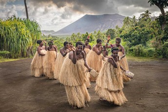 Frauen des Dorfes Imaio während einer Kastom-Tanzaufführung, im Hintergrund der rauchende Vulkan Yazur.