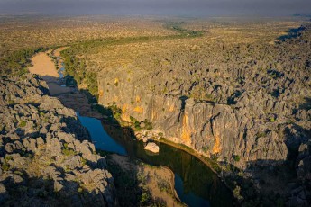 Durch die Jahrmillionen alte Windjana-Schlucht in der Kimberley-Region schlängelt sich der Lennard River wie ein türkisgrünes Band zwischen den bis zu 100 Meter hohen Kalksteinwänden hindurch, die einst ein urzeitliches Barriereriff bildeten und heute Heimat für Süßwasserkrokodile und seltene Gesteinsformationen sind.