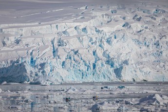 Two Zodiacs appear like toys before the immense glacier front at Meusnier Point. Crevasses and seracs tower high as houses. Maintaining respectful distance is vital for survival.