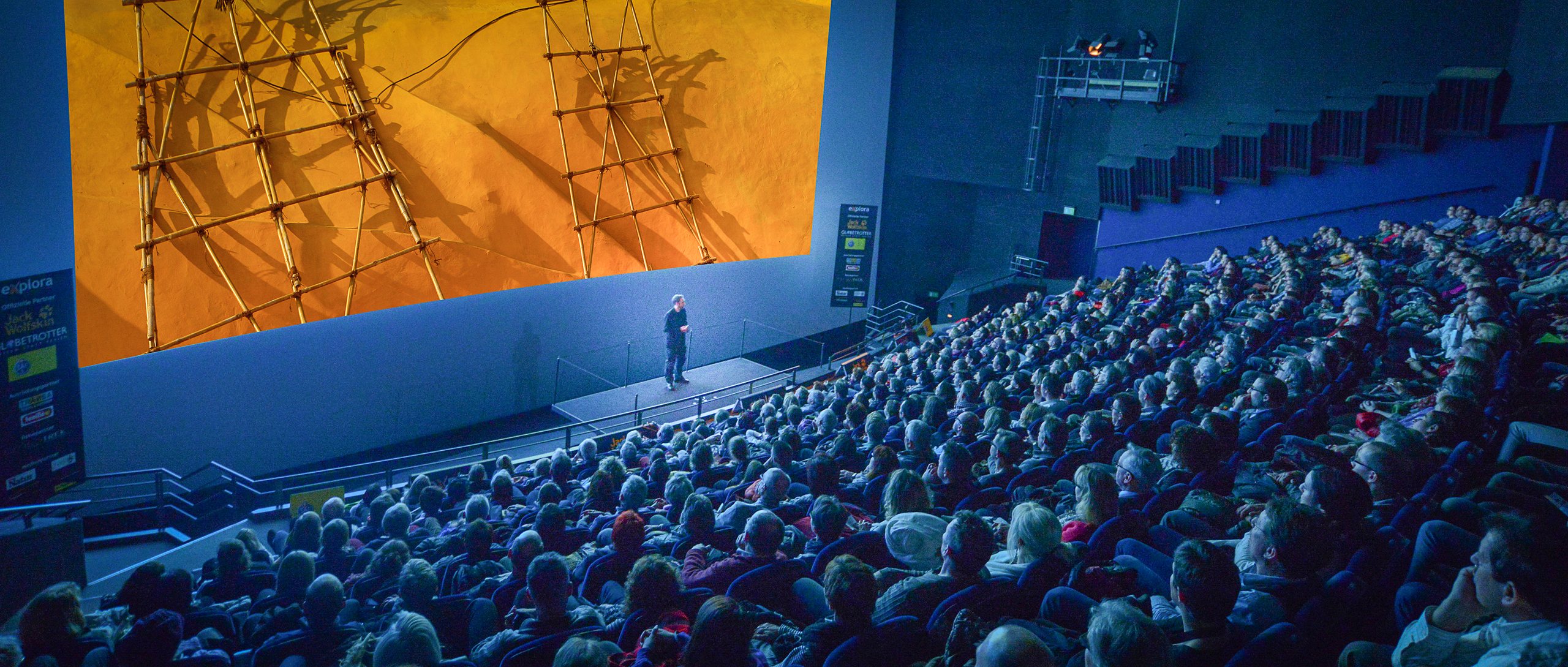 Malte Clavin auf der Bühne im IMAX-Kino Luzern vor vollem Saal